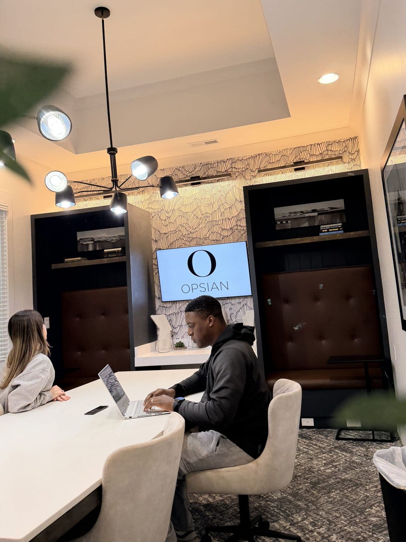 Two people working at laptops in the Opsian office