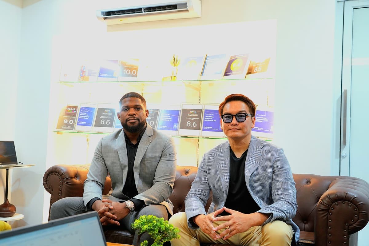 Patrick Neba Fabs Che and Peerawat Hansirikul seated in front of the RoomQuest awards wall